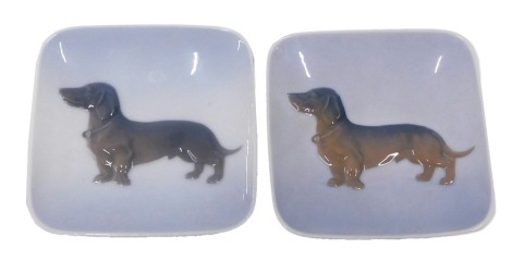 A pair of Royal Copenhagen porcelain pin trays, each decorated with a Dachshund, 10cm wide.