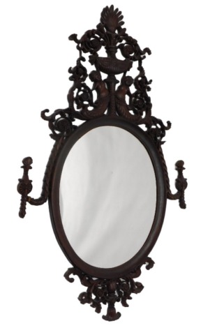 A Continental hardwood wall mirror, the elaborate frame carved with mermaid type figures, urns, scrolls, flowers, etc., with an oval plate, 124cm high. (AF)