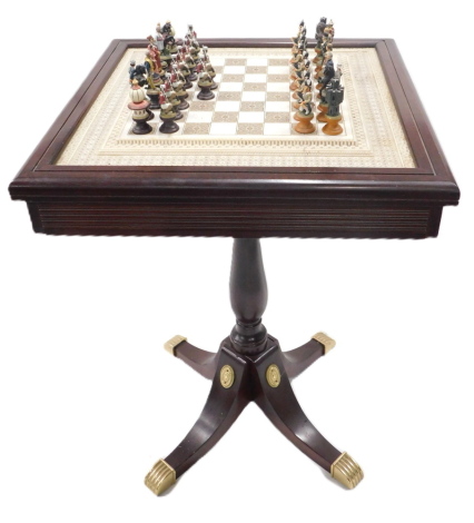 A Raj chess set, comprising The British Knights, Indian Knights & Rooks, some with certificates, and a reproduction mahogany games table, the resin top with chess board, within elaborate borders, above a drawer, 51cm wide.