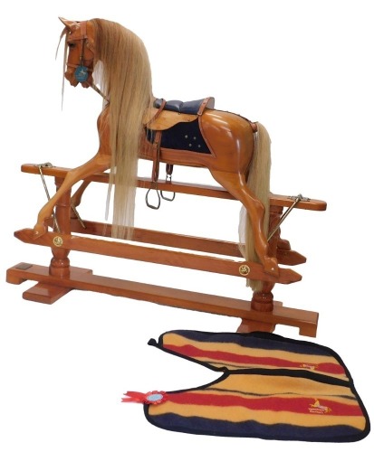 A Stevenson Brothers of England fruitwood rocking horse, wearing original blanket, on trestle base, applied with plaque, dating to 1998, 142cm long.