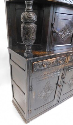 A carved oak court cupboard, the top with a panelled door, decorated with lozenge, on cup and cover supports, the base with two drawers and two doors, on styles, 150cm high, 120cm wide. - 3