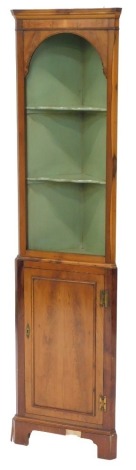 A narrow yew corner cabinet, the open top with a green painted interior, above a panelled door, on bracket feet, 70cm high, 42cm wide.