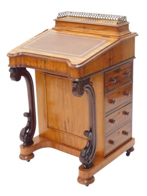 A Victorian mahogany Davenport, the top with a hinged pen and ink section, with pierced brass gallery, the fall with brown leather insert, enclosing a fitted interior, above an arrangement of four drawers to side, and four false drawers, on scrolling supp