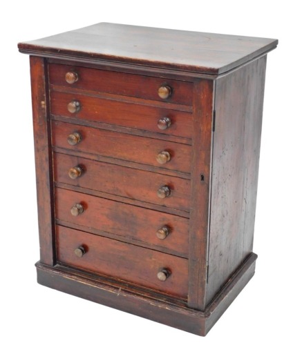 A Victorian stained pine Wellington chest, with an arrangement of six drawers, each with turned wood handles, and hinged retainer, on a plinth, 73cm high, 56cm wide.