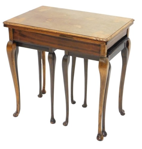 A 1920s burr walnut rectangular nest of three tables, the largest with fold over beige lined top, 56cm wide.