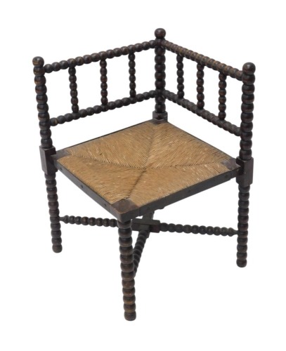 A late 19th/early 20thC bobbin turned corner chair with rush seat.