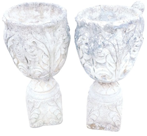 A pair of composition stone garden planters, each of cylindrical form, with scroll carved decoration, on pedestal base, 50cm high, 44cm diameter.