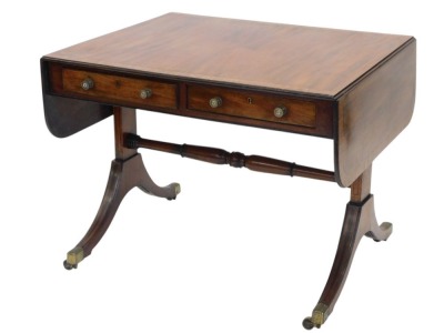 A Regency mahogany and rosewood cross banded sofa table, the rectangular top with rounded corners, above two frieze drawers on plain end supports, united by a stretcher, sabre legs, with brass castors, 145cm wide, 73cm deep.