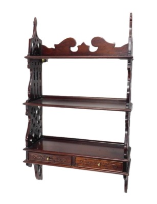 A hardwood wall shelf, with a shaped crest, two shelves, flanked by pierced sides and two drawers, 95cm high, 52cm wide.