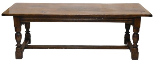 An oak refectory table in 17thC style, the rectangular planked top with a moulded frieze on turned supports, with flat H stretcher, 77cm high, 230cm wide, 91cm deep.