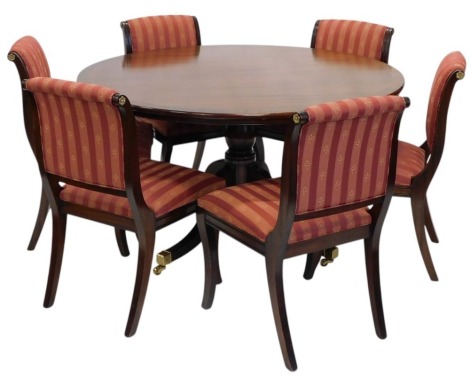 A reproduction mahogany dining table, the circular cross banded top on a turned column and four splayed legs with brass castors, 75cm high, 136cm diameter, and a set of six regency style dining chairs, with padded back and seat, on sabre legs.