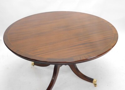 A reproduction mahogany dining table, the circular cross banded top on a turned column and four splayed legs with brass castors, 75cm high, 136cm diameter, and a set of six regency style dining chairs, with padded back and seat, on sabre legs. - 3