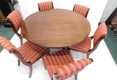 A reproduction mahogany dining table, the circular cross banded top on a turned column and four splayed legs with brass castors, 75cm high, 136cm diameter, and a set of six regency style dining chairs, with padded back and seat, on sabre legs. - 4