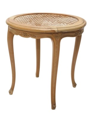 A Continental pale beech occasional table, the circular top with a cane and glass insert, the frieze carved with flowers on cabriole legs, 62cm high, 60cm diameter.