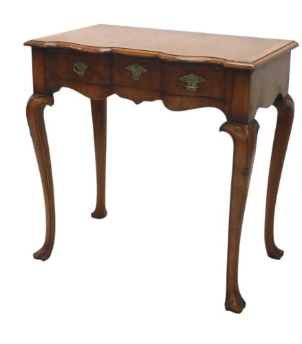 A Titchmarsh and Goodwin burr walnut and walnut lowboy or side table, the rectangular top with a moulded edge, and a serpentine front above a frieze drawer with engraved brass handles, on cabriole legs with pointed pad feet, 77cm wide.