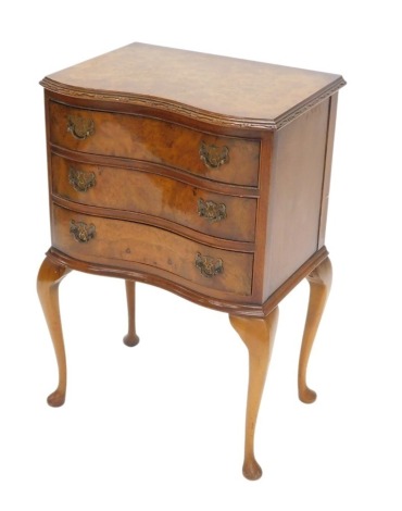 A burr walnut side cabinet, the figured top with a moulded edge and a concave front above three drawers, on cabriole legs with pad feet, 78cm high, 50cm wide.