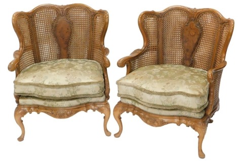 A pair of 1920s double caned bergere armchairs, with serpentine seats and carved cabriole legs. NB. We have specific vendor instructions to sell WITHOUT RESERVE.