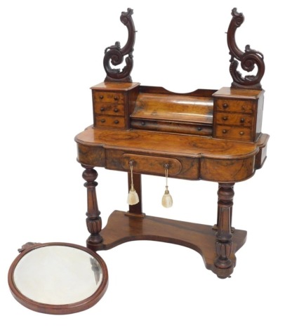 A Victorian figured walnut dressing table, the top with an oval mirror plate and carved scrolling supports above an arrangement of seven drawers, the lobed break front base with a moulded edge above an ovoid frieze drawer, on turned fluted legs with conca