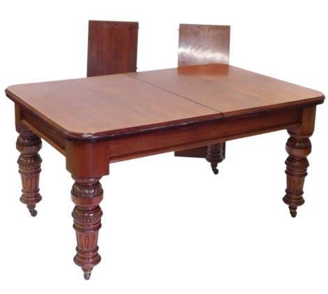 A Victorian mahogany extending dining table, the rectangular top with rounded corners and a moulded edge, on carved turned supports with ceramic castors, two loose leaves, 76cm high, 227cm long, 100cm wide.