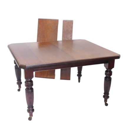 A late 19th/early 20thC mahogany extending dining table, the rectangular top with canted corners and a moulded edge, on turned reeded tapering legs with ceramic castors, two loose leaves, 75cm high, 180cm long, 106cm wide.