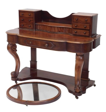 A Victorian mahogany dressing table, the top with scroll carved supports and arrangement of six drawers flanking a hinged compartment, the lobed base with a moulded edge, and a frieze drawer, on cabriole supports with shaped under tier, 120cm wide.