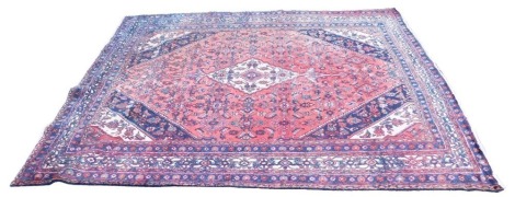 A large Persian star rug, with a central medallion in red, on a blue ground, multiple border, 345cm x 253cm.