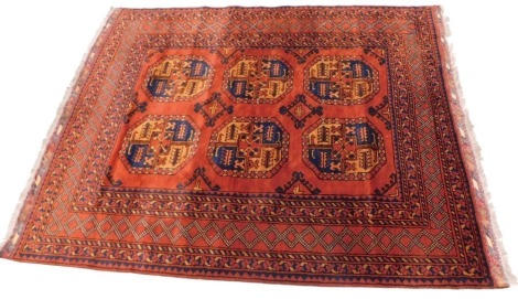 A Turkoman type Afghan rug, with two rows of medallions, on a rust coloured ground, one wide, six narrow border, 93cm x 158cm.