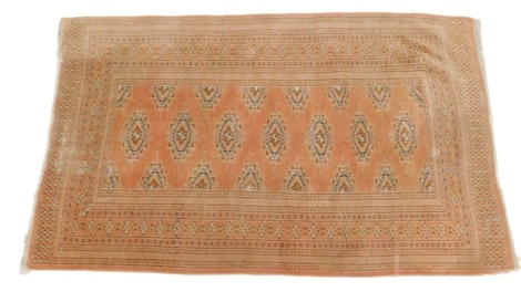 An Afghan style rug, with a design of medallions, on a coral ground, within multiple borders, 150cm x 82cm.