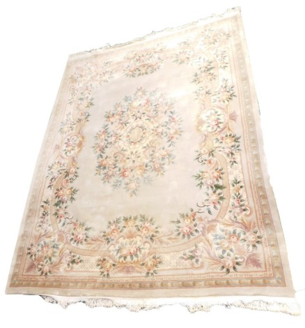 A washed Chinese woollen carpet, with central reserve and traditional stylised flower heads and foliage, scrolls, red, green, blue and brown, on a beige ground, with blue and beige border, 367cm x 276cm.