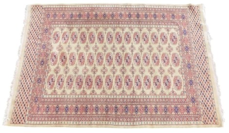 A Bokhara yellow ground rug, decorated centrally with three rows of medallions within one wide and multiple narrow borders, 185cm x 125cm.