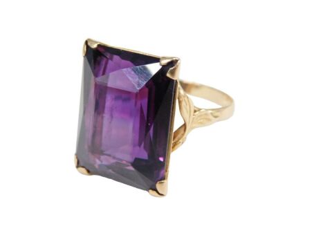 A 20thC alexandrite synthetic corundum dress ring, set with rectangular cut purple colour change stone, 19mm x 15mm x 8.85mm, approx 30.27ct, claw set, on plain band, yellow metal stamped 18k, ring size P, 9.9g all in.