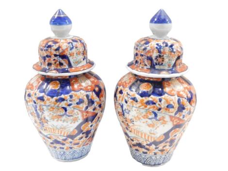 A pair of late 19th/early 20thC Japanese Imari vases and covers, each decorated with flowers, etc., 28cm high. (AF)