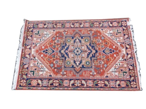 A Persian rug, with a design of a medallions on a red ground, cream spandrels, multiple borders, 120cm x 176cm.