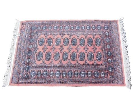 An Afghan rug, with a design of medallions, on a pink ground, with multiple borders.