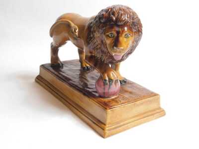 An early 19thC brown glazed Staffordshire lion, After Ralph Wood, with the front right paw resting on a magenta coloured ball, on a rectangular base, 33cm long. - 2