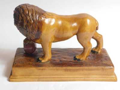 An early 19thC brown glazed Staffordshire lion, After Ralph Wood, with the front right paw resting on a magenta coloured ball, on a rectangular base, 33cm long. - 3