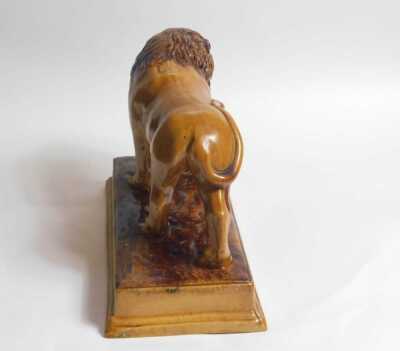 An early 19thC brown glazed Staffordshire lion, After Ralph Wood, with the front right paw resting on a magenta coloured ball, on a rectangular base, 33cm long. - 4