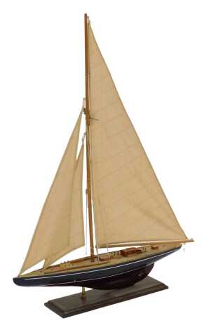 A wooden model of a sailing yacht, with a black hull, on an integral base, 87cm high.