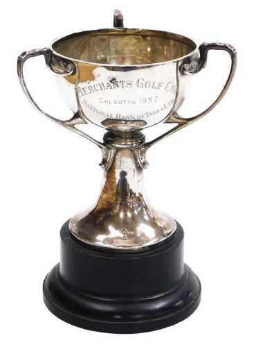A 20thC Indian colonial silver trophy, of triple handle form, engraved 'Merchants Golf Cup, Calcutta 1957, National Bank of India Ltd', verso winner's names, Hamilton & Co, Calcutta & New Delhi, 9.72oz, with an ebonised socle.