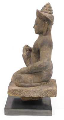 A Khmer sandstone figure of Varuna, in a seated door keeper pose as guardian of the west, possibly 10th/11thC, modelled wearing a sampot, with a jewelled headdress and collar, on a block fragment, raised on a black, rectangular base, 72cm high. Provenance - 2