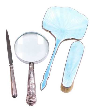 A George VI silver and turquoise guilloche enamel hand mirror, together with a clothes brush, magnifying glass with silver King's pattern handle, and a paper knife with silver handle. (4)