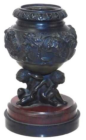 A 19thC bronze Grand Tour urn, cast with a band of classical symbols, heads and animals, raised on a triple putti base, on a circular marble stand, 11.5cm high.