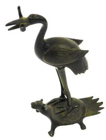 A Japanese bronze candlestick, modelled as a crane on a minogame mythical turtle with hairy tail, lacking candle sconce, 18cm high.