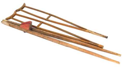 A pair of vintage wooden crutches, 127cm high, together with a pair of stilts, 148cm high.