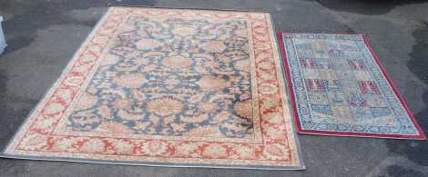 Two rugs, a large rug 100% wool, with a gold ground, red border and floral design, 235cm long x 170cm wide, together with a small hall rug, red border with geometric gridded pattern with floral design, manmade material, 150cm long x 78cm wide. (2)