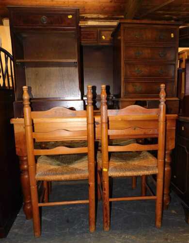 A pine kitchen table, with four pine ladder back chairs, rush upholstered seating, a pair of bedside cabinets, and a mahogany bookcase with two frieze drawers, table measures 122cm long x 82cm wide.