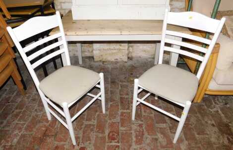 A pine kitchen table, with painted legs, 73cm high, the top 123cm x 76cm, together with two ladder back chairs.