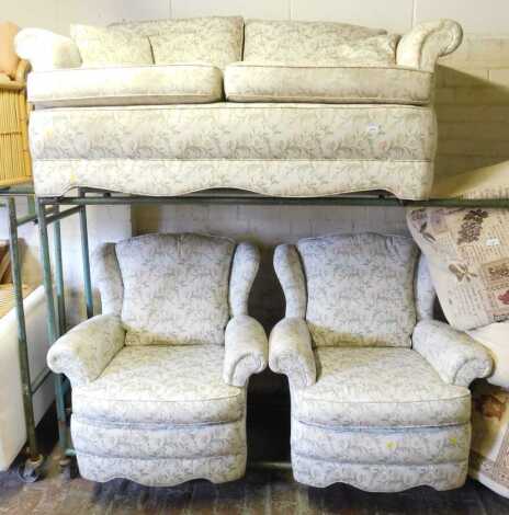 A two seater sofa, together with two matching armchairs, upholstered in floral fabric. (3)