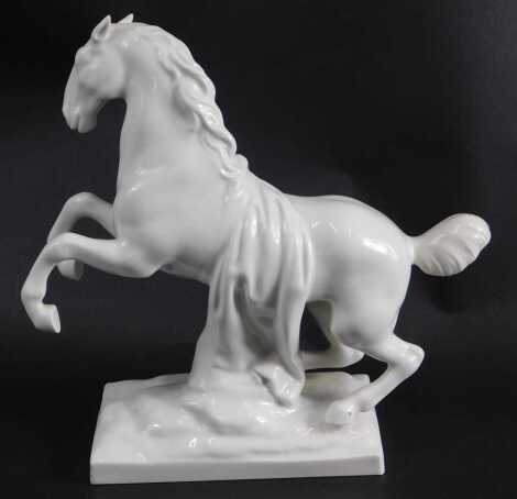 A German porcelain white glazed rearing horse, mark in blue to rectangular base, 20cm high.