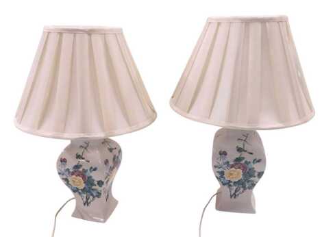 A pair of ceramic table lamps, each with printed decoration of flowers and birds, with pleated shade, 54cm high. WARNING! This lot contains untested or unsafe electrical items. It is supplied for scrap or re-conditioning only. TRADE ONLY